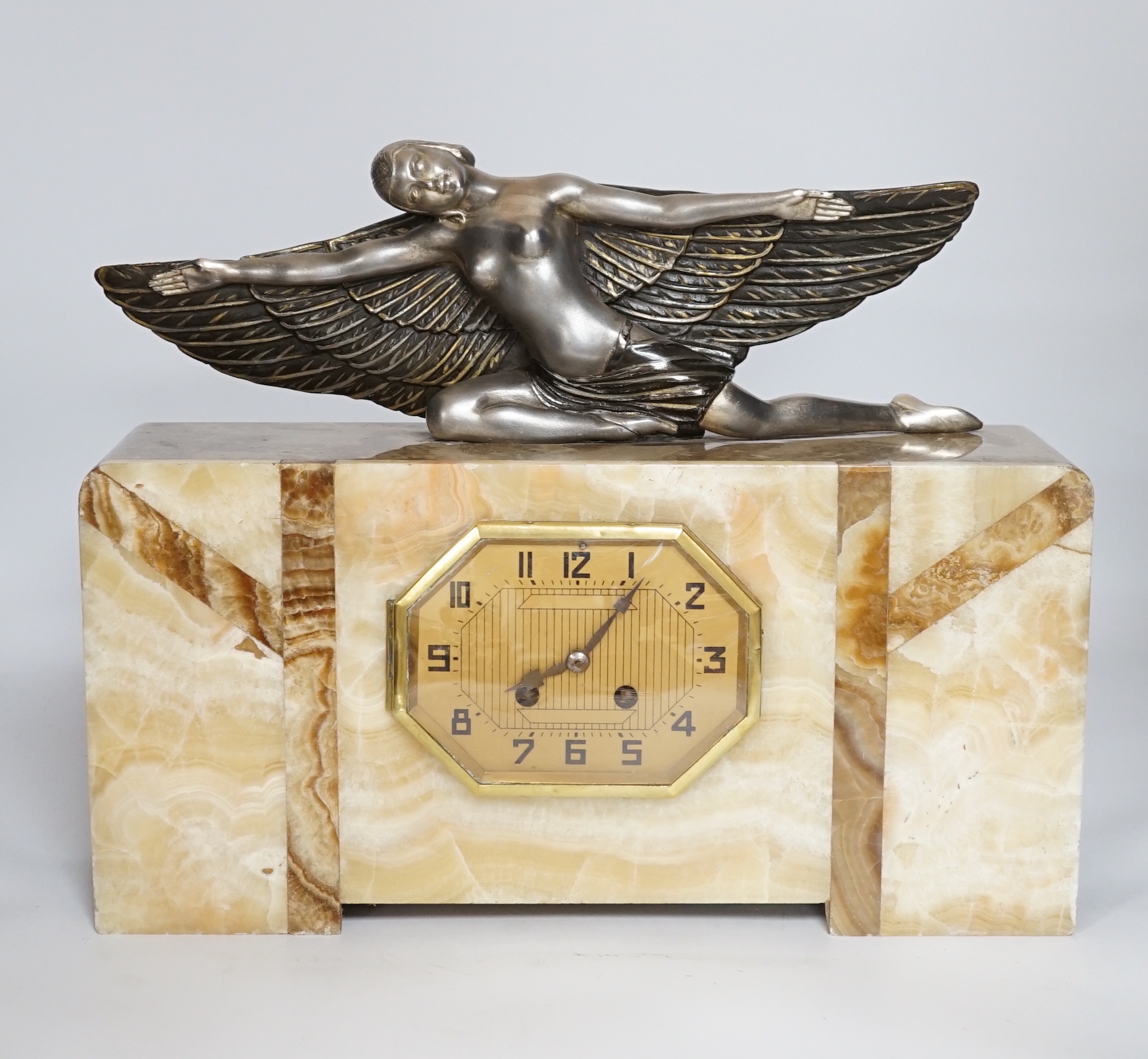 An Art Deco marble mantel clock with a metal winged woman, with French pendulum movement striking on a bell, 38cm wide, 30cm high